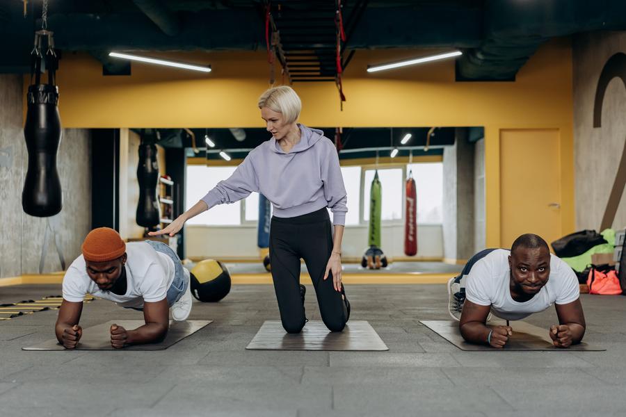 Trainer coaching two clients through a plank exercise