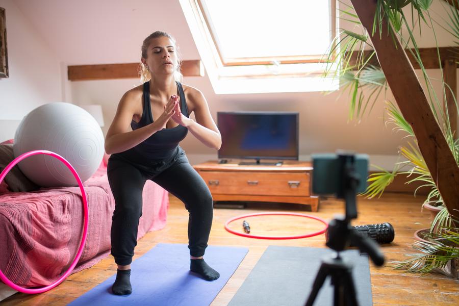 Person recording a home workout on a phone tripod