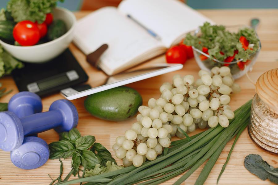 Fresh whole foods including grapes, avocado, tomatoes, and dumbbells